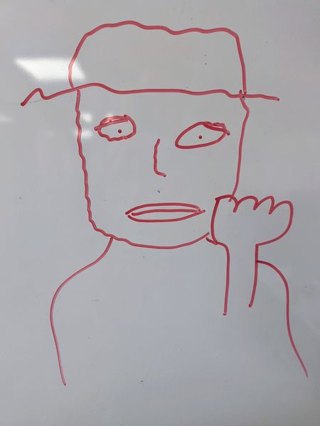 The image shows a simple red marker drawing of a person on a whiteboard. The person is depicted with a hat, a neutral expression, and a hand raised to their face, possibly in a thinking or gesturing pose. The drawing is minimalistic, with basic shapes and lines.